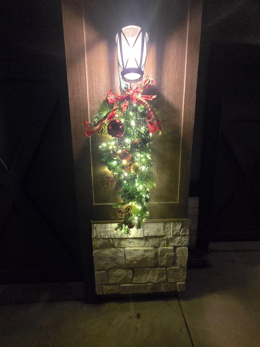 Festive garland with lights and ribbon on stone pillar