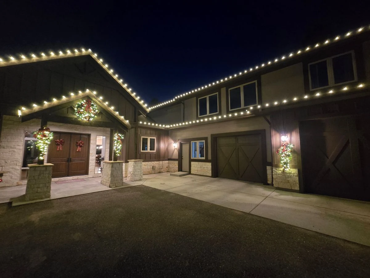 Craftsman estate with warm white roofline lights and lit wreaths
