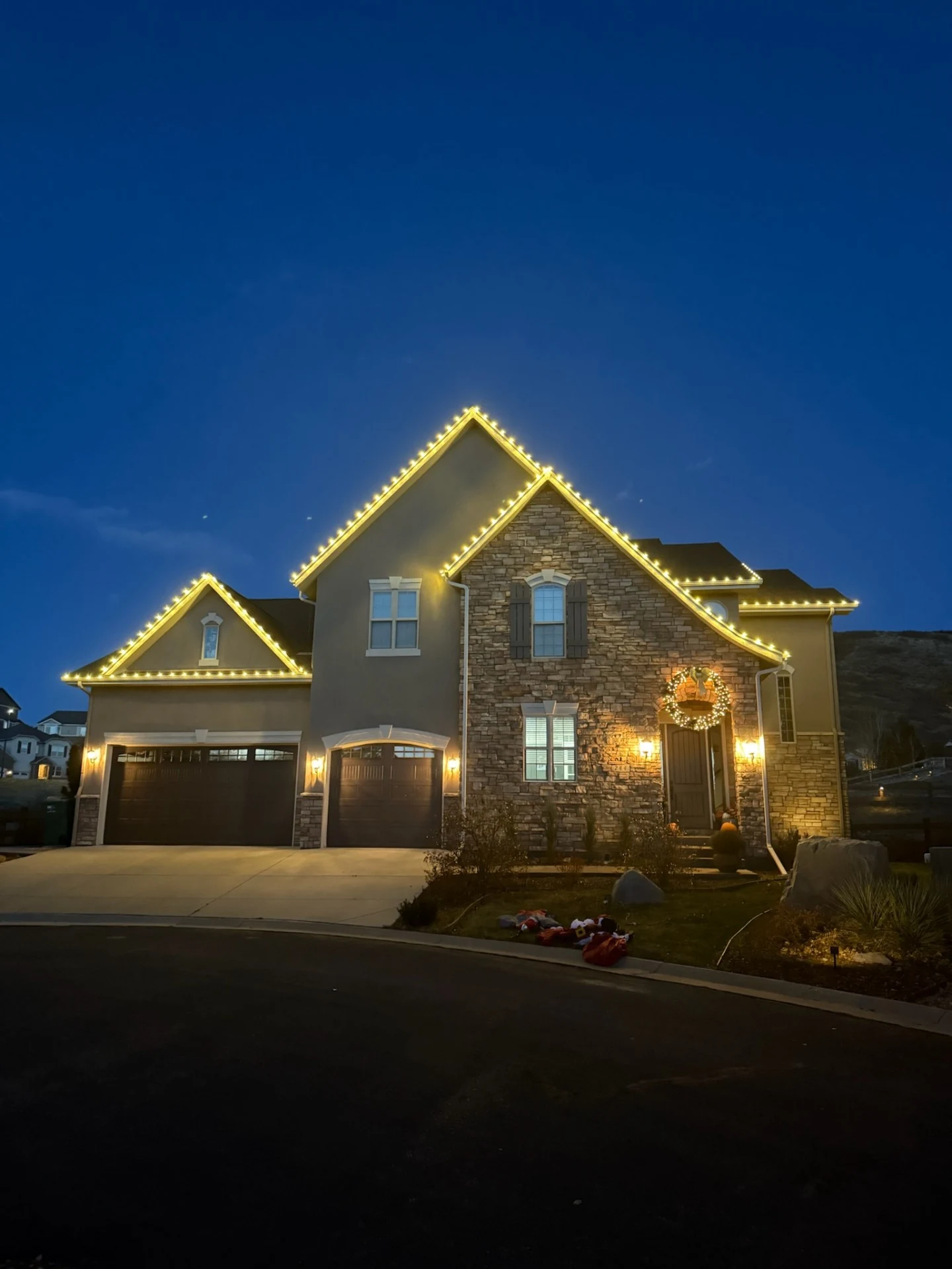 Two-story stone home with warm white roofline outline at dusk