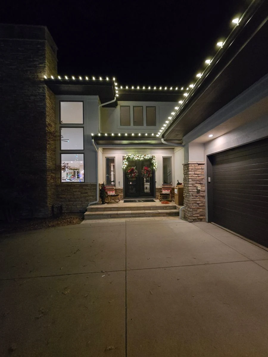 Modern home with warm white roofline lights and holiday wreath
