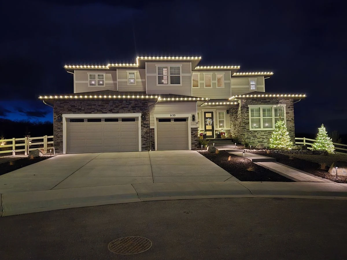 Modern two-story home with full roofline lights and lit trees
