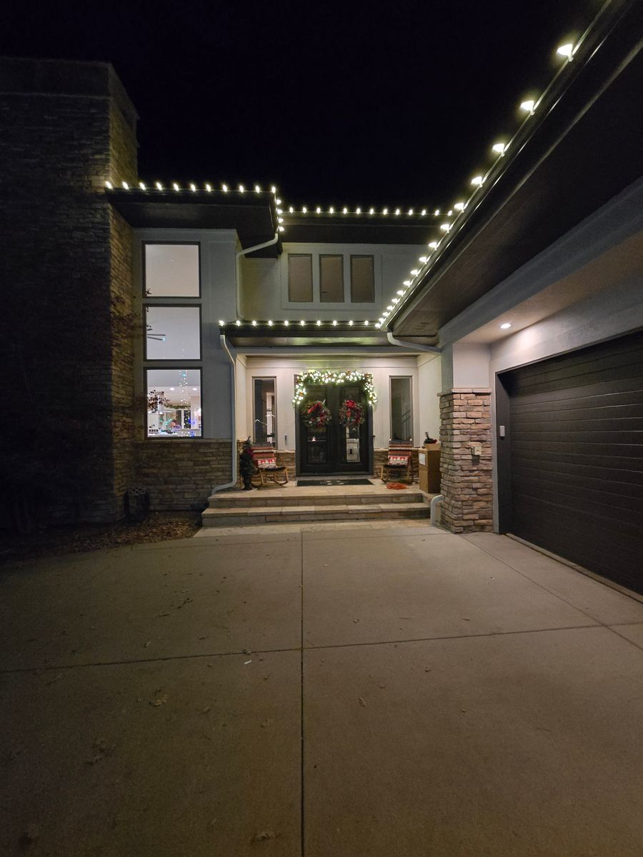 Modern home with warm white roofline lights and holiday wreath
