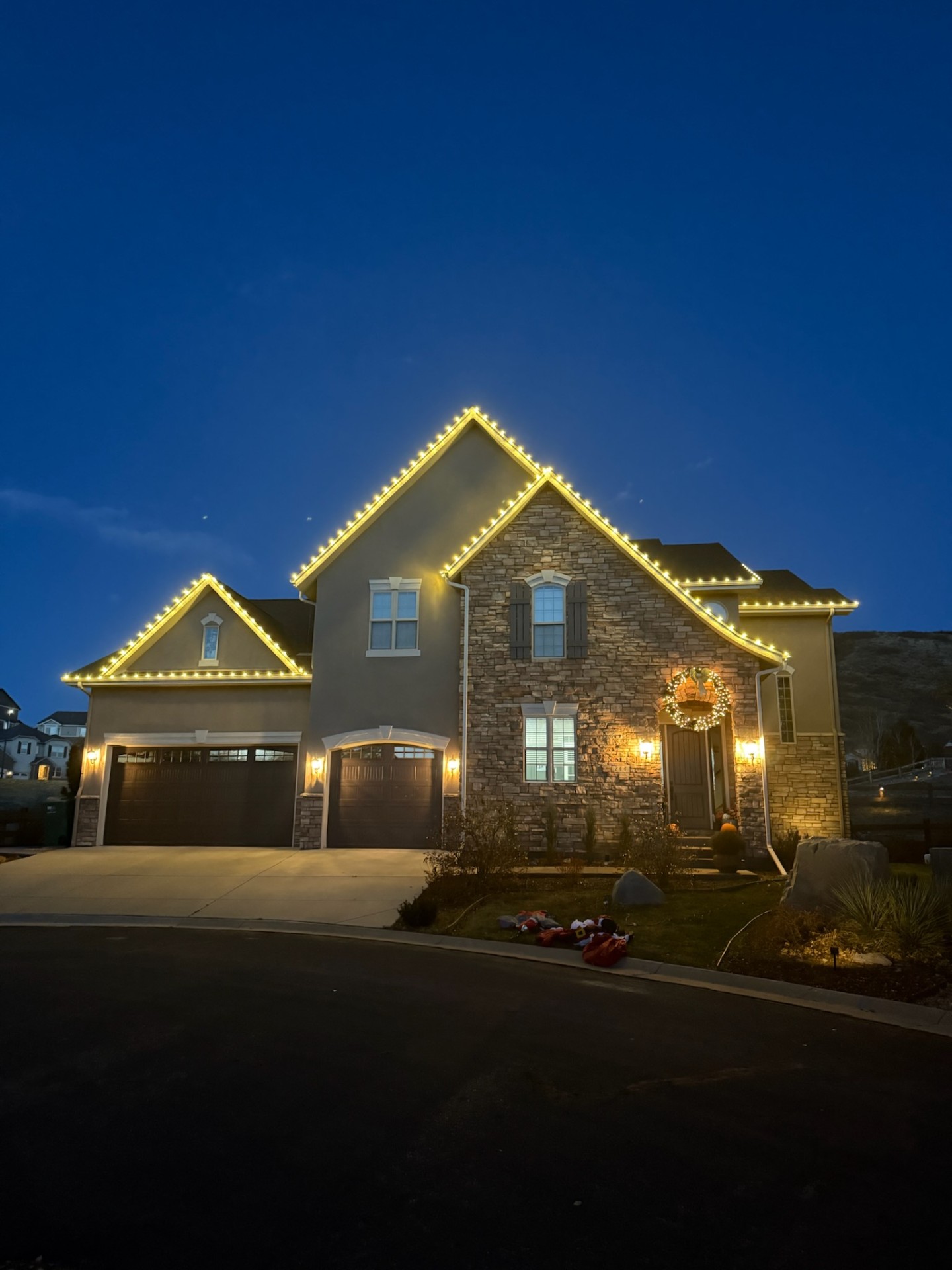 Two-story stone home with warm white roofline outline at dusk